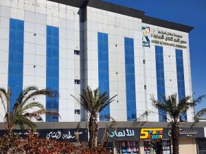 a building with palm trees in front of it at سديم الفخر 2 للشقق الفندقية in Taif