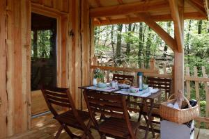 einen Tisch und Stühle auf einer Veranda einer Hütte in der Unterkunft Les Cabanes des Benauges in Arbis