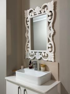 a bathroom with a white sink and a mirror at SaltySky Penthouse in Gansbaai