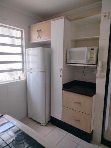 a small kitchen with a refrigerator and a microwave at Ap 2quartos atras do shopping in Votorantim +11 photos