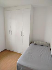 a white bedroom with a bed and white cabinets at Ap 2quartos atras do shopping in Votorantim