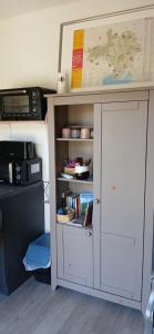 a desk with a book shelf and a microwave at Studio clim 4-5 pers animaux, mai oct spa et piscine in Saint-Ambroix