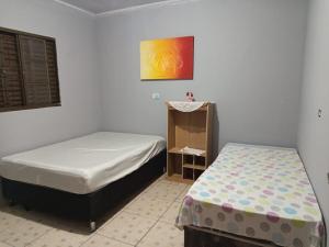 a bedroom with two beds and a painting on the wall at Trabalhamos com casas e alojamentos para empresas in Cianorte