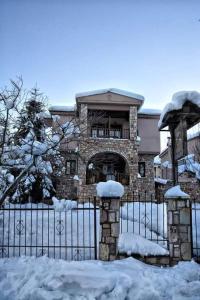 a building with a fence covered in snow at Akrolimnia in Kalyvia
