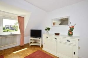 a living room with a television and a white dresser at Malvenhof, App OG in Wenningstedt