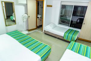 a small room with two beds and a mirror at HOTEL DON QUIJOTE in Pereira +21 photos