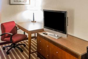 Habitación con escritorio, TV y silla. en Economy Inn & Suites, en Warren