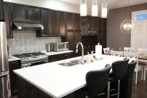 a kitchen with black cabinets and a white counter top at Luxury 5BR Home with Spa Bath in Burlington +114 photos