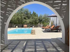an archway over a swimming pool with chairs and an umbrella at Dar Néliah Djerba in Djerba +3 photos