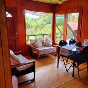 ein Wohnzimmer mit einem Tisch und einem Fenster in der Unterkunft Chiloe Profundo in Chonchi