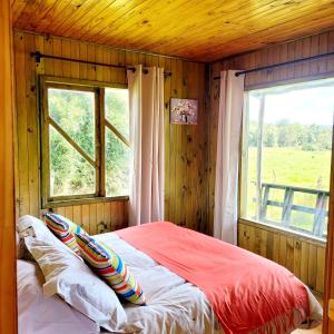 ein Schlafzimmer mit einem großen Fenster und einem Bett mit Kissen in der Unterkunft Chiloe Profundo in Chonchi
