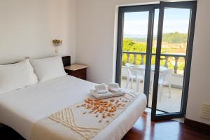 a bedroom with a bed and a balcony with a table at Jantesta Guest House in Coimbra +172 photos