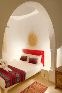 a bedroom with a bed with a red headboard at Dar Néliah Djerba in Djerba