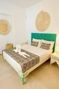 a bedroom with a bed with a green headboard at Dar Néliah Djerba in Djerba