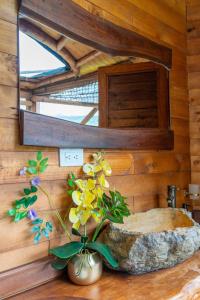 a bathroom with a mirror and a vase with flowers at Glamping Corazón del Molino in Ubaque +57 photos