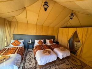 a bedroom with two beds in a tent at hagra luxury camp Merzouga in Merzouga