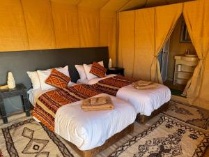 a bedroom with two beds with towels on them at hagra luxury camp Merzouga in Merzouga +12 photos