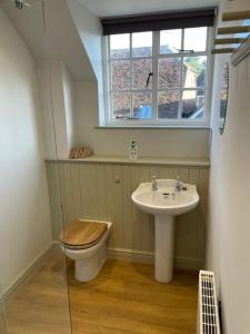 a bathroom with a toilet and a sink and a window at Escape to Blacksmiths Cottage in Cuckfield +11 photos
