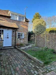 a brick house with a white door and a brick yard at Escape to Blacksmiths Cottage in Cuckfield