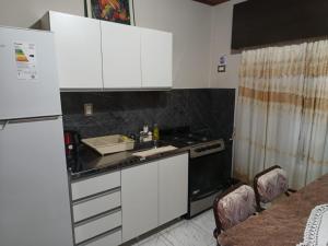 a kitchen with white cabinets and a sink and a refrigerator at Alojamiento Fiara in Chajarí