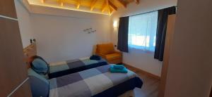 a bedroom with a bed and a chair and a window at Cá du Mattu in Villa Pehuenia