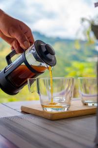 a person pouring tea from a tea kettle into a glass at Glamping Corazón del Molino in Ubaque