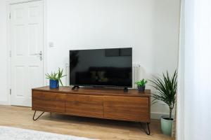 a flat screen tv sitting on top of a wooden dresser at West London Spacious Modern House Garden Driveway in London +38 photos
