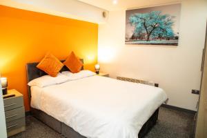 a bedroom with a white bed with an orange wall at Studio Close To Alhambra And Bradford Live Walk To Stations in Bradford
