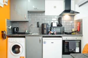 a kitchen with a sink and a washing machine at Studio Close To Alhambra And Bradford Live Walk To Stations in Bradford