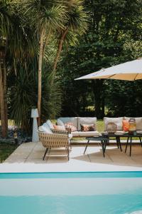 a patio with a couch and a table next to a pool at Les Arbres Rouges in Sucé