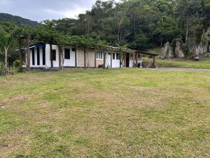 an old house with a grass field in front of it at Camping Fazenda Serramar in Palhoça