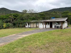 a small white house on a grassy field at Camping Fazenda Serramar in Palhoça