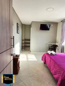 a bedroom with a bed with a pink blanket at Paraíso Hotel Ubaté in Ubaté