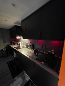 a kitchen with black cabinets and a sink at Cozy Garden Apt - 8ight Havens in Folkestone