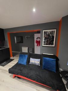 a living room with a black couch with blue pillows at Cozy Garden Apt - 8ight Havens in Folkestone