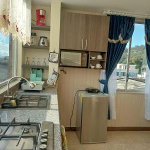 a kitchen with a stove and a sink and a window at Departamento azul de 2 hab en la Victoria, cerca de universidades con garaje in Ibarra