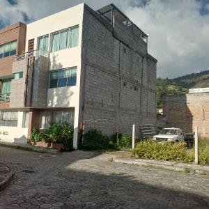 a building with a car parked in front of it at Departamento azul de 2 hab en la Victoria, cerca de universidades con garaje in Ibarra