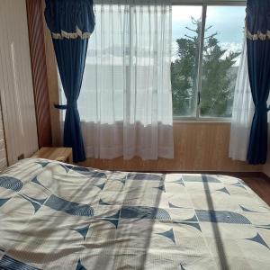 a bed in front of a window with blue curtains at Departamento azul de 2 hab en la Victoria, cerca de universidades con garaje in Ibarra