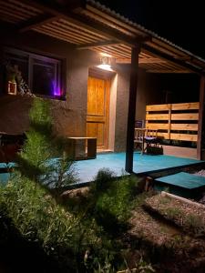 a porch of a house with a wooden door at night at cabañas UMA RAYMI in Juella