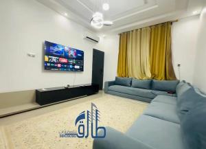 a living room with a blue couch and a flat screen tv at Studio SAHRAOUI in Nouakchott