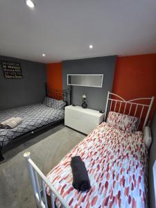 a bedroom with two beds in a room with orange walls at Cozy Garden Apt - 8ight Havens in Folkestone