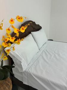 a white bed with yellow flowers on top of it at Eco House1 in Santos +4 photos