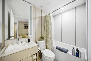 a bathroom with a sink and a toilet and a mirror at Spacious Condo with 2 Beds Unbeatable Location in Toronto
