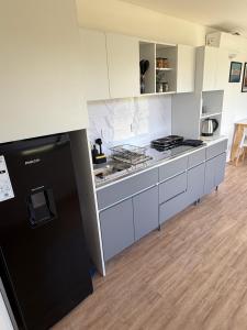 a kitchen with white cabinets and a black refrigerator at Complejo Nomade Home in Marcos Juárez