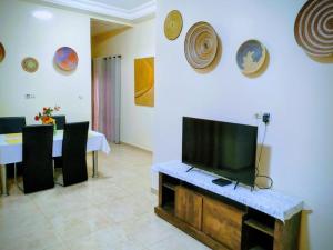 a living room with a tv and a table with chairs at Villa Julien 2 chambres in Rufisque