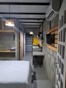 ein Schlafzimmer mit einem weißen Bett und eine Küche in der Unterkunft Rustica e Charmosa in Santa Cruz Cabrália