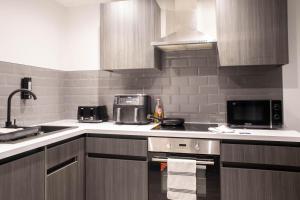 a kitchen with a sink and a stove top oven at Luxury Serviced Apartment With Super King Bed Workspace WiFi & Netflix Washer Dryer Close Parking in Bradford