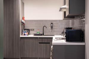 a kitchen with a sink and a microwave at Luxury Serviced Apartment With Super King Bed Workspace WiFi & Netflix Washer Dryer Close Parking in Bradford +3 photos