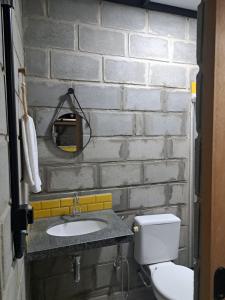 ein Badezimmer mit Toilette und Waschbecken und einer Ziegelwand in der Unterkunft Rustica e Charmosa in Santa Cruz Cabrália