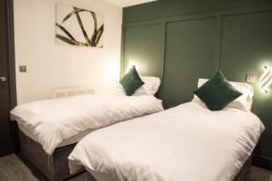 two beds sitting next to each other in a room at Luxury Serviced Apartment With Super King Bed Workspace WiFi & Netflix Washer Dryer Close Parking in Bradford